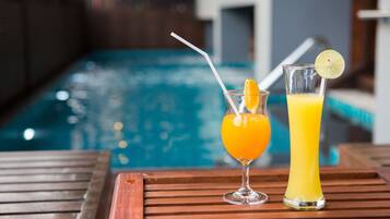 Two drinks on a wooden table near a pool.