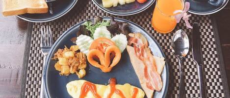 A breakfast setting with toast, fruit, bacon, eggs, and a cup of coffee on a checkered table.