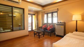 A hotel room with a bed, a desk, a chair, a refrigerator, and a window.