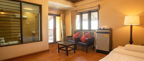 A hotel room with a bed, a desk, a chair, a refrigerator, and a window.