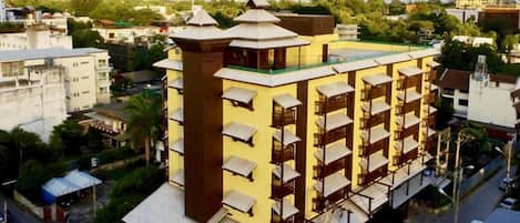 Un hotel de varios pisos con una torre central, balcones y una terraza en la azotea.