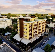 Un hotel de varios pisos con una torre central, balcones y una terraza en la azotea.