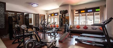 Un gimnasio con equipo de ejercicio diverso, una cinta de correr y un espejo grande.