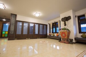 A spacious lobby with a polished floor, traditional wooden doors, and a decorative elephant head sculpture.