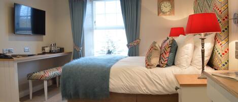 A bedroom with a bed, bedside tables, a desk, a TV, and a window with curtains.
