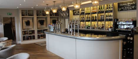 A bar area with a central counter, multiple taps, and a wine display.