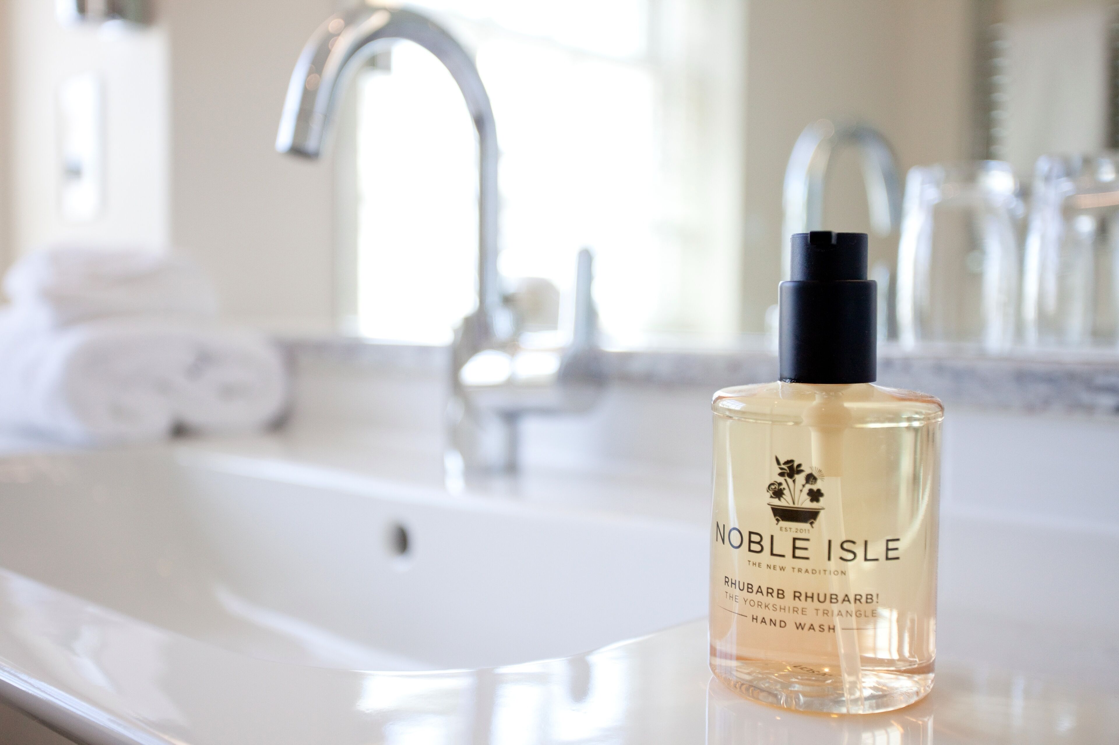 Una botella de jabón de manos Noble Isle sobre una encimera de baño.