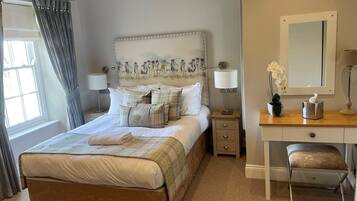 A neatly arranged bedroom with a bed, bedside tables, a desk, and a chair.