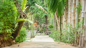 Un sentier qui traverse un jardin luxuriant, agrémenté de structures en bambou et de verdure.
