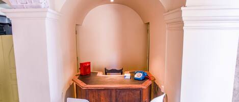 A small, private bar area with a wooden counter, two white chairs, a red telephone, and a blue telephone.