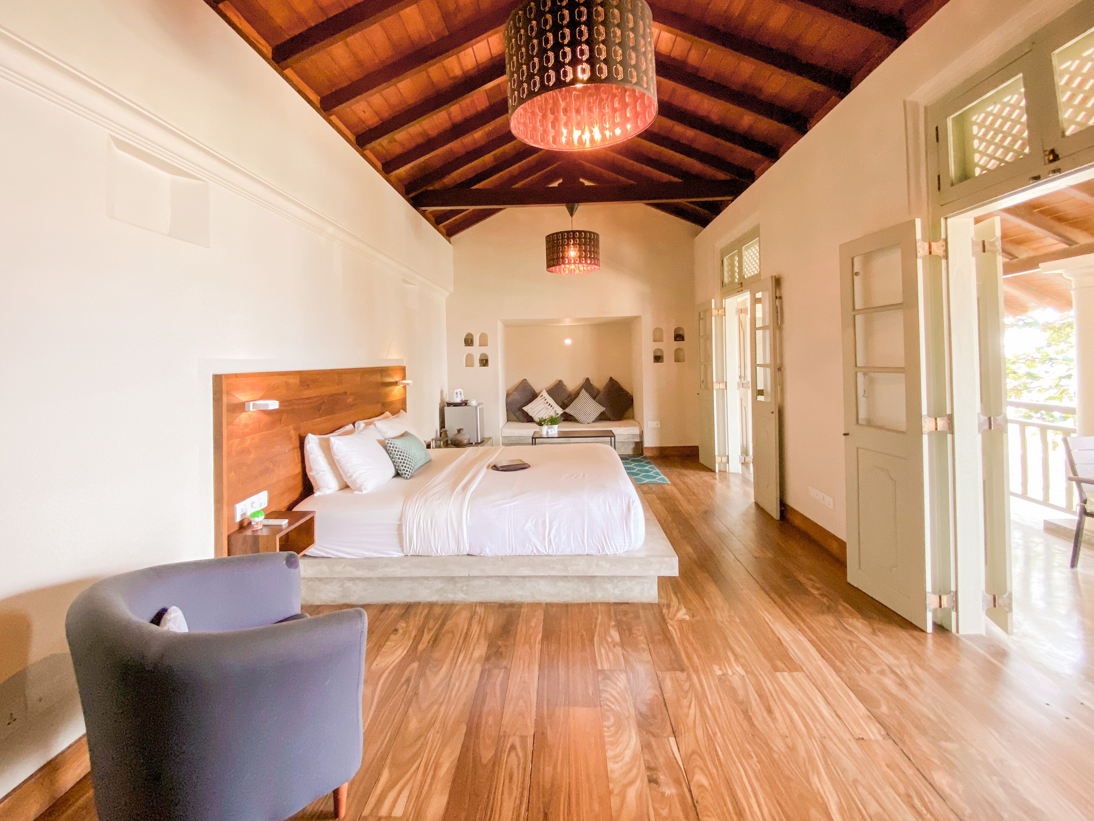 A spacious bedroom with a large bed, wooden ceiling, and a view of the outdoors.