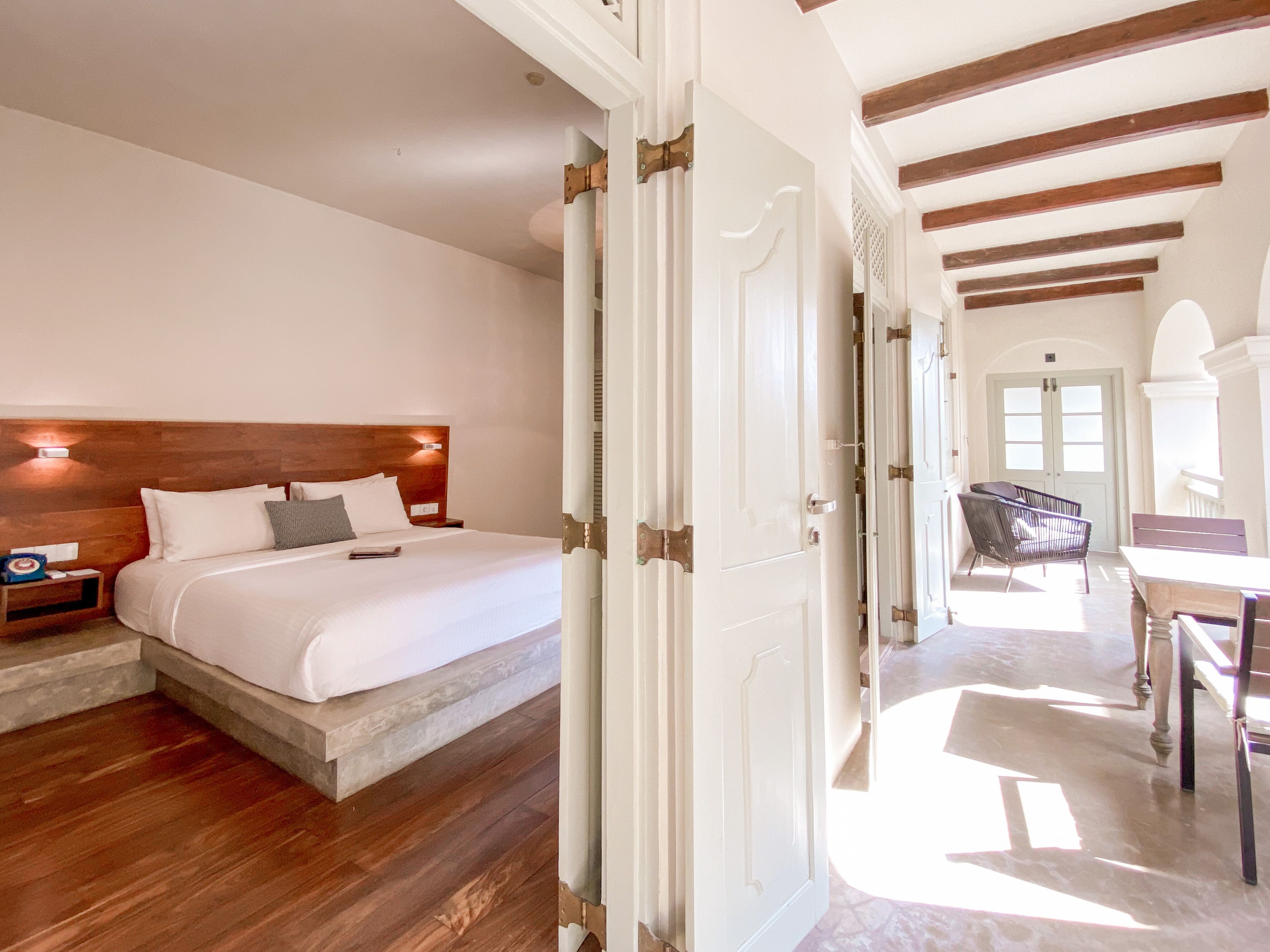 Una habitación de hotel con cabecera de madera, cama con ropa blanca, mesita de noche y escritorio con silla.