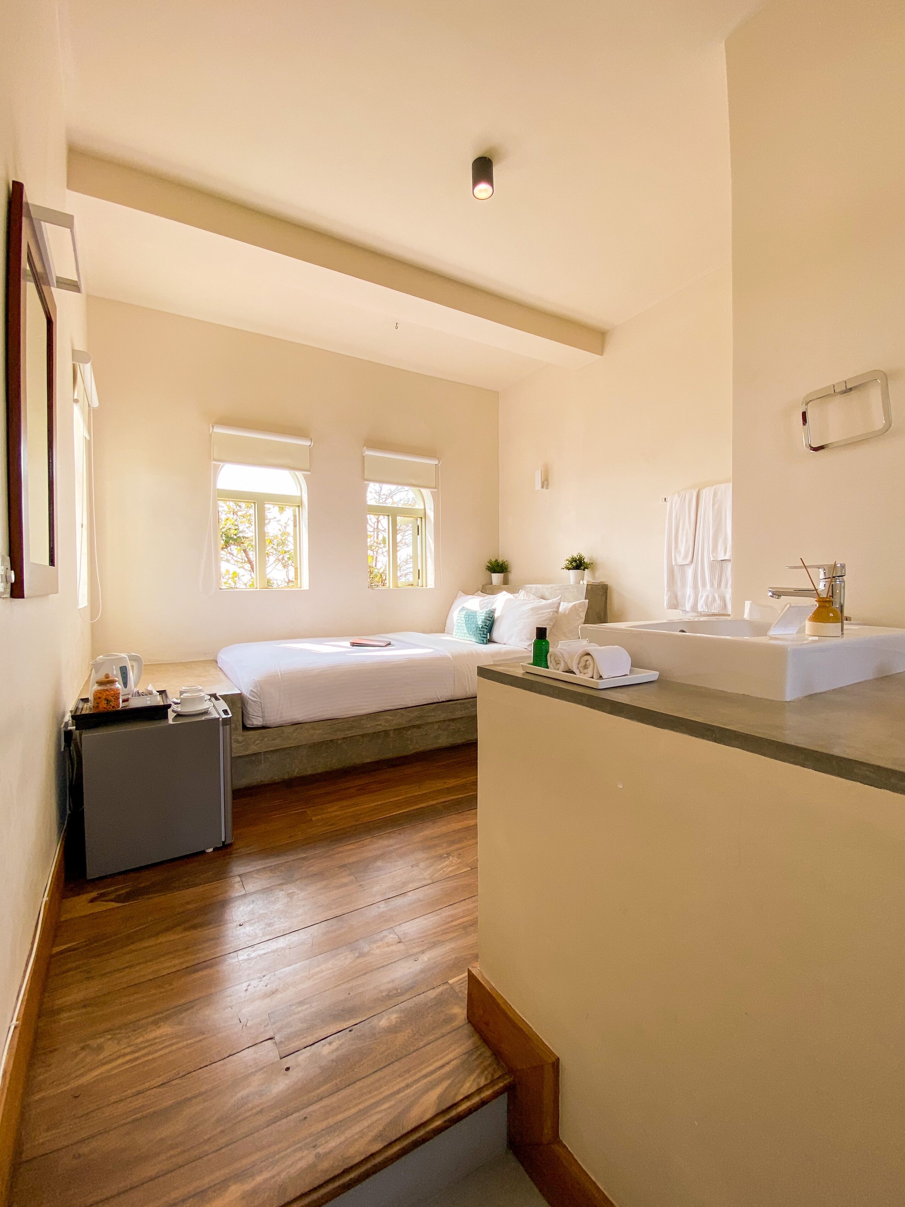 Una habitación de hotel con una cama, un escritorio pequeño, un lavamanos y una ventana.