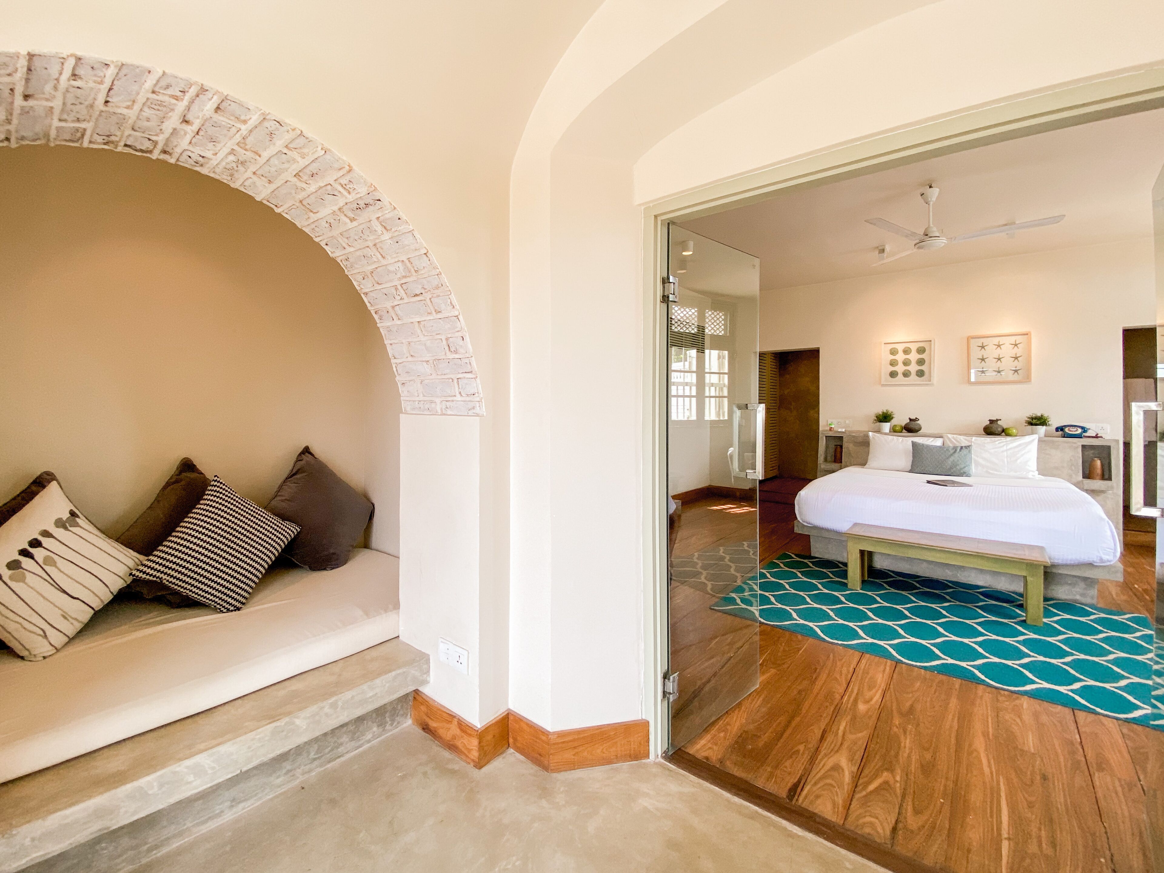 Un dormitorio con cama, sofá con cojines, suelo de madera y pared de azulejos.