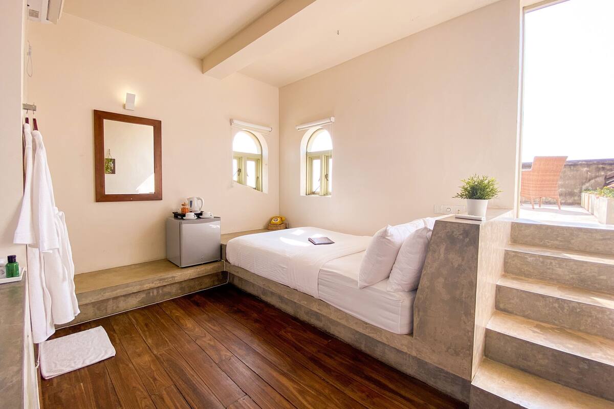 Una camera da letto con un letto, un comodino, uno specchio e una finestra.