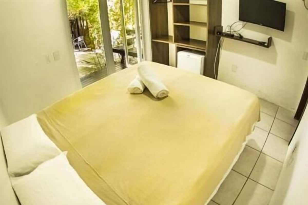 Une chambre d’hôtel avec un lit, un téléviseur fixé au mur et une vue sur l’extérieur.
