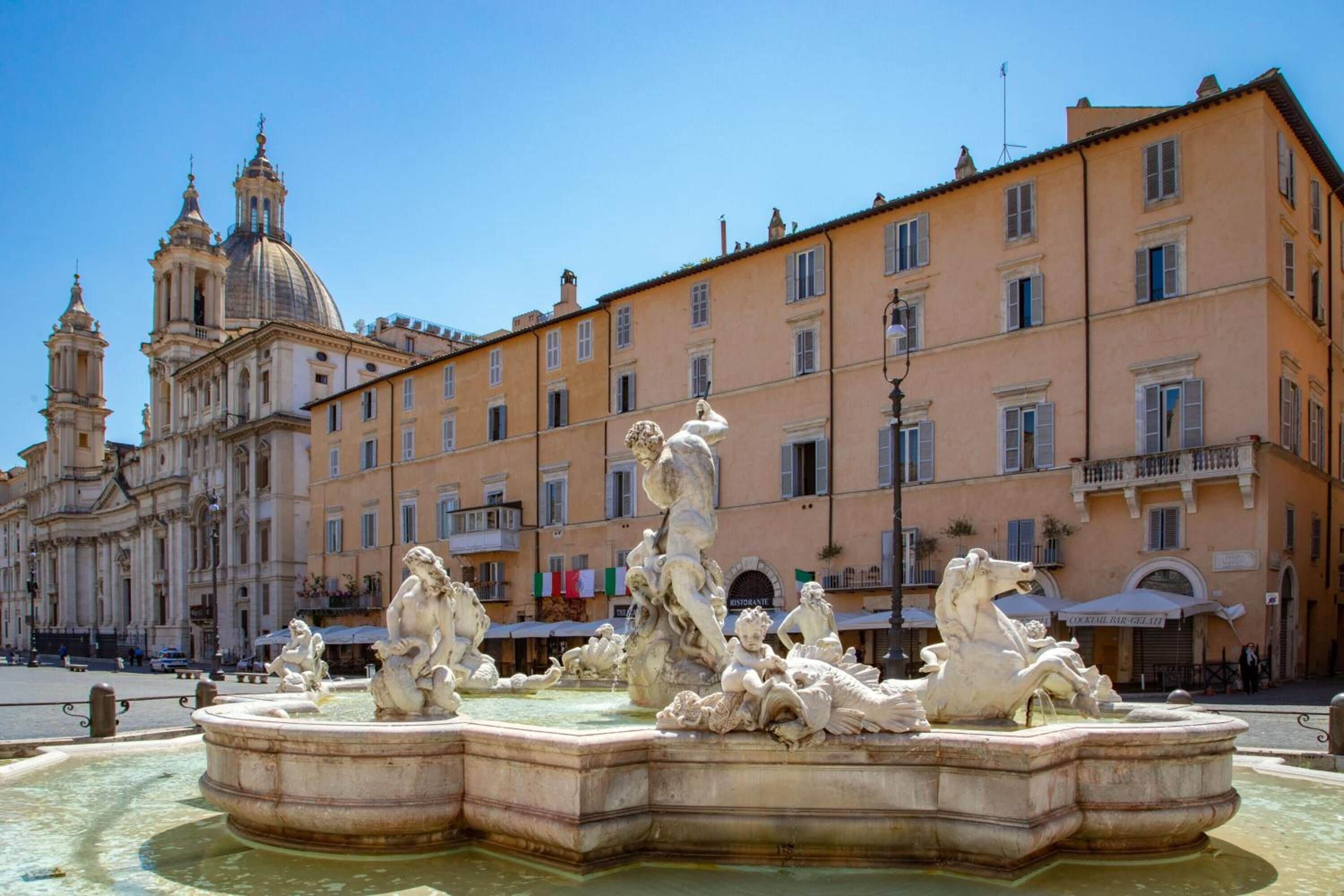 A historic fountain with classical sculptures in a square, surrounded by classical architecture and buildings.
