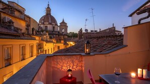 A rooftop terrace with a table, chairs, a glass of wine, candles, and a decorative lantern. - The Right Place 4U Roma Navona Terrace Luxury Rooms (Rome)