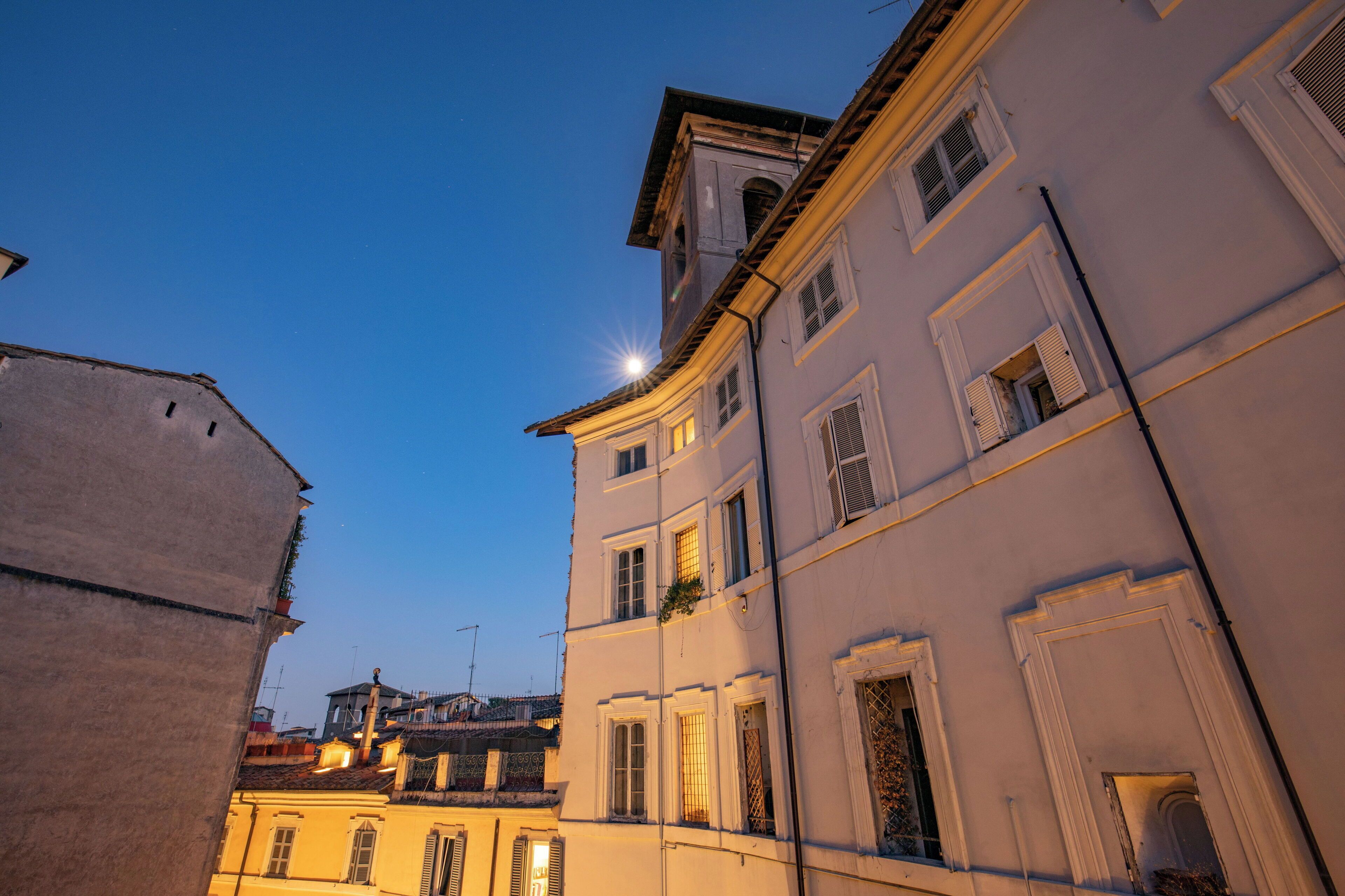 Un bâtiment doté de nombreuses fenêtres et de balcons, présentant un style architectural classique avec des murs blancs et un toit plat.