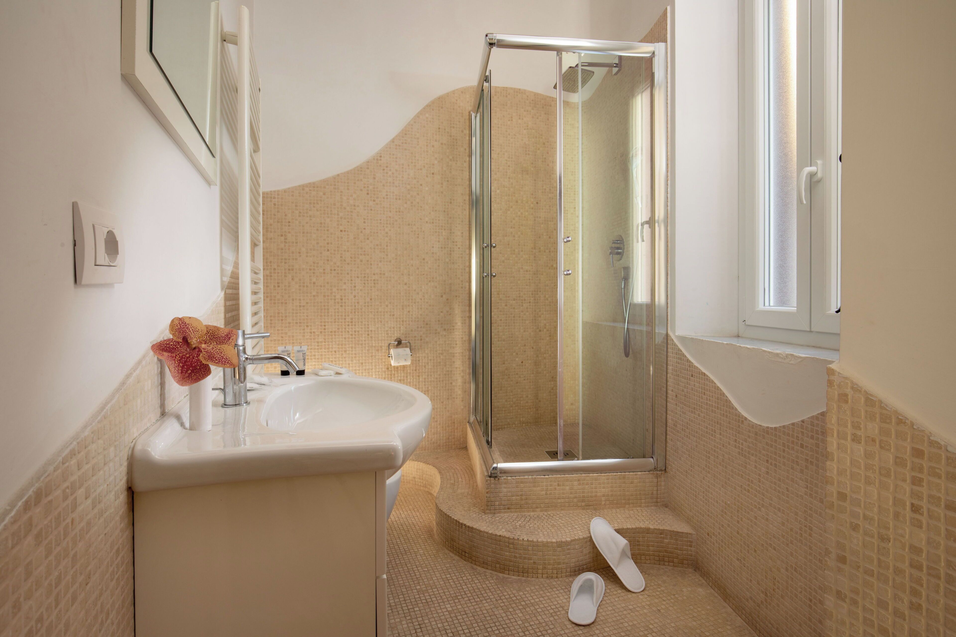 Ein Badezimmer mit Duschkabine aus Glas, Waschbecken und Handtuch auf dem Boden.