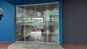 Ingresso di un edificio moderno con porta in vetro, livello superiore visibile e pavimento piastrellato.