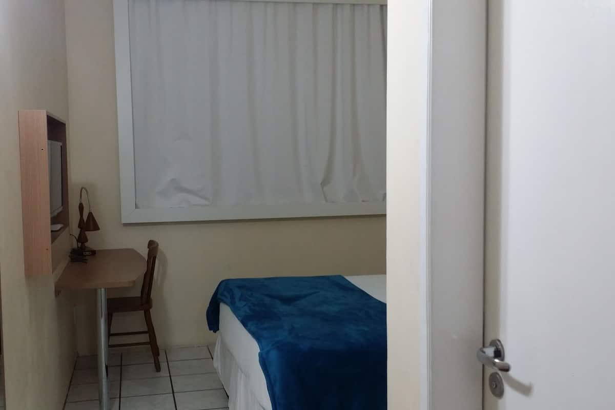 Ein kleines, sauberes Zimmer mit einem Bett, einem Schreibtisch und einem Stuhl.