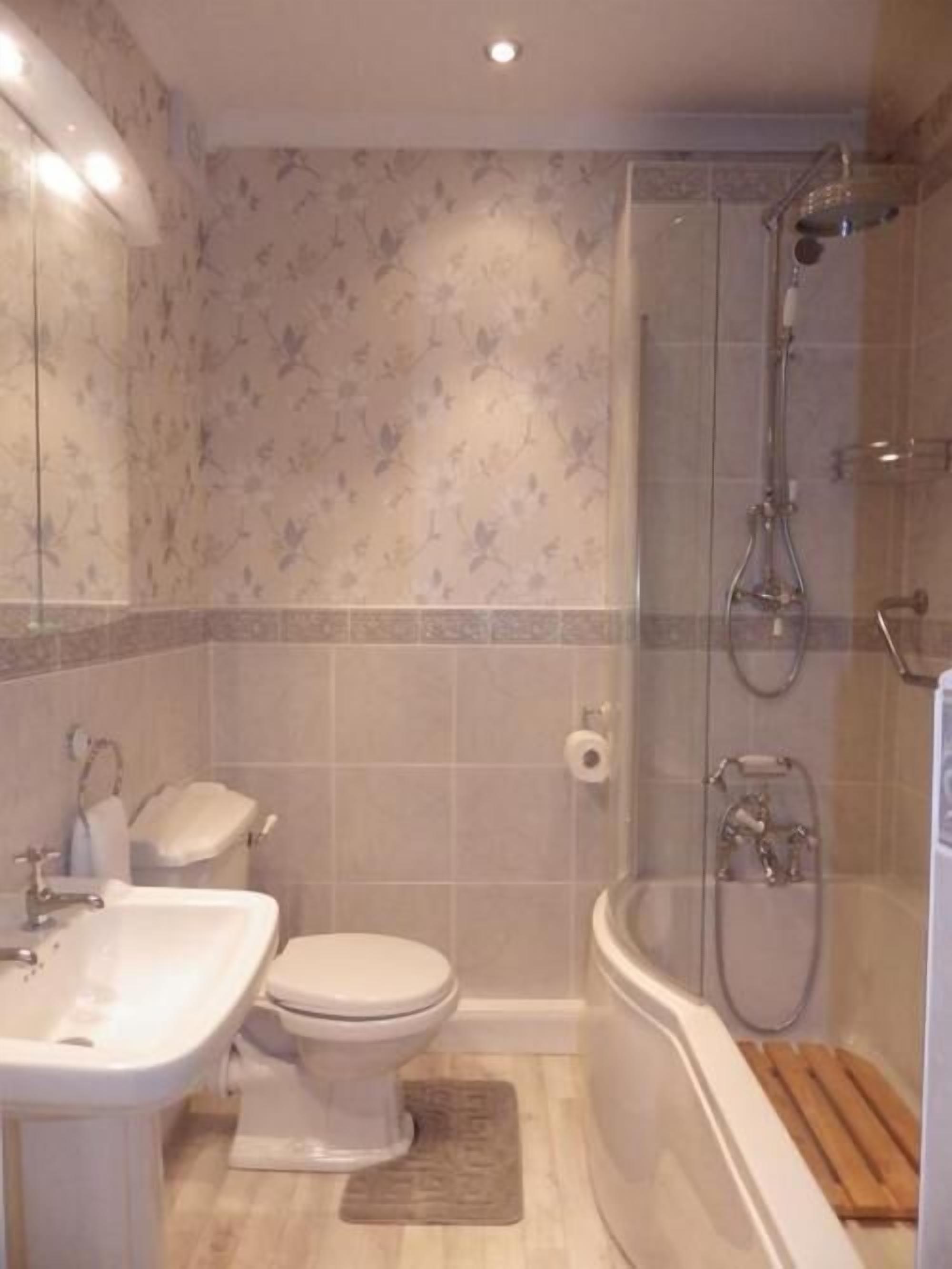 Et badeværelse med toilet, vask og brusebad.