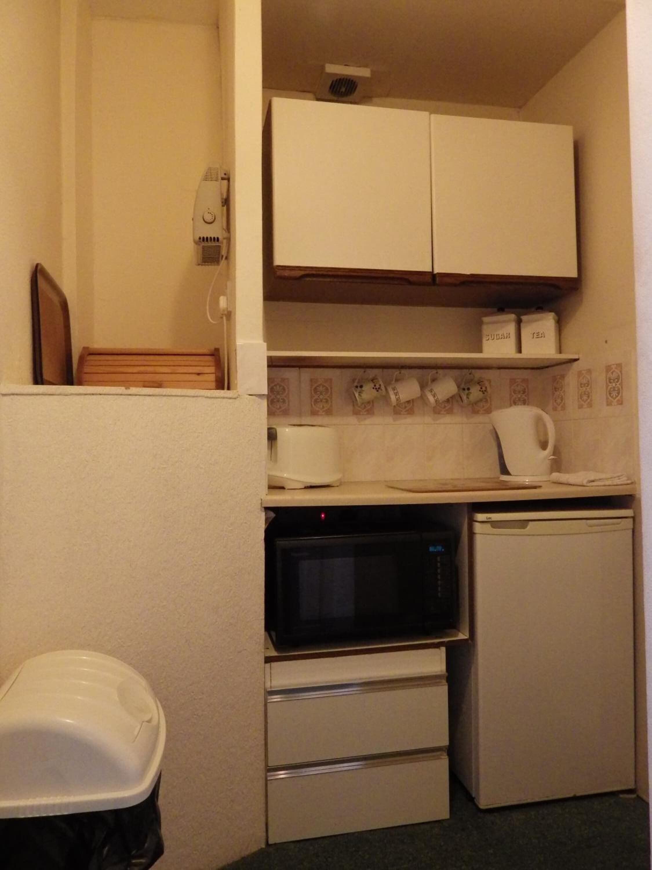 Una kitchenette compacta con microondas, un refrigerador pequeño y una cafetera.