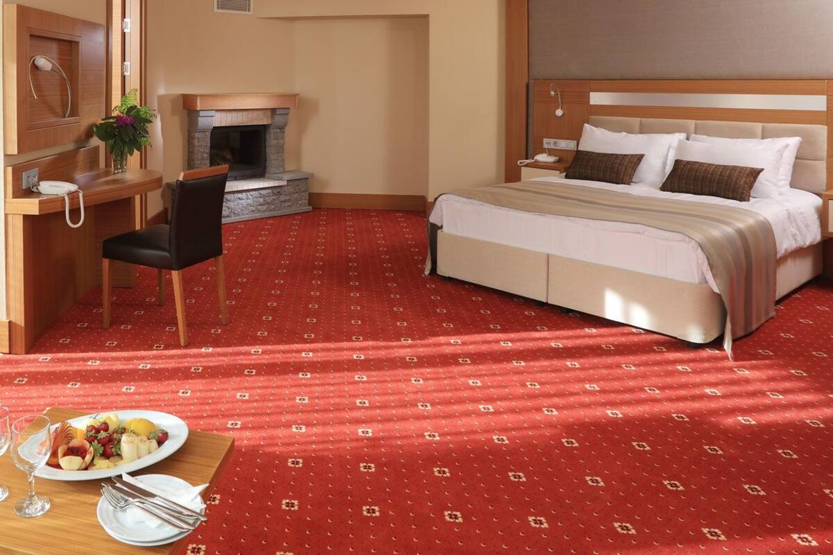 A hotel room with a bed, a sofa, a dining table with plates and glasses, a fireplace, and a telephone.