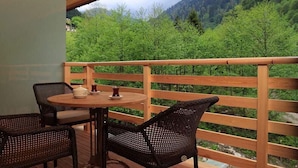 A wooden deck with a table and chairs, overlooking a forested mountain area. - Kaçkar Resort Hotel (Camlihemsin)