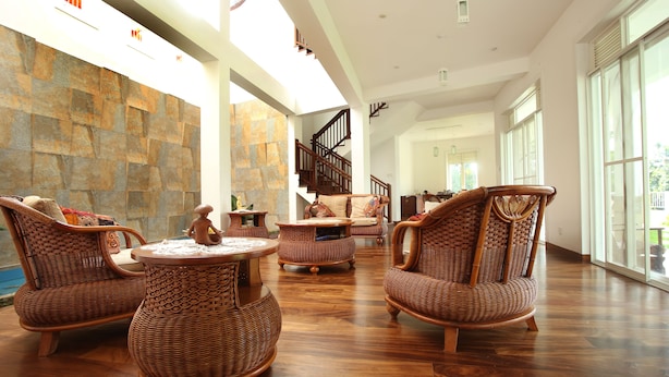 A spacious lobby with wicker furniture, a stone wall, and a staircase leading to upper floors. - Sunlit Villa (Harispattuwa)