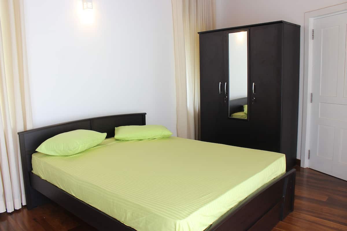 A bedroom with a bed, a wardrobe, and a door.