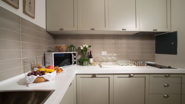 A kitchen with beige cabinets, a microwave, and a fruit basket on the counter. - San Giuliano Inn - Adults Only (Florence)
