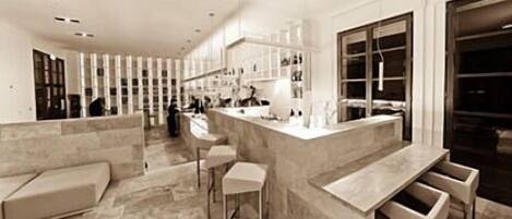 A modern kitchen with a bar area, marble countertops, and a seating area with bar stools.