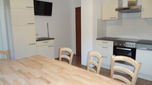 Une cuisine avec des meubles blancs, une cuisinière et un four à micro-ondes. On y trouve également une table à manger avec des chaises.