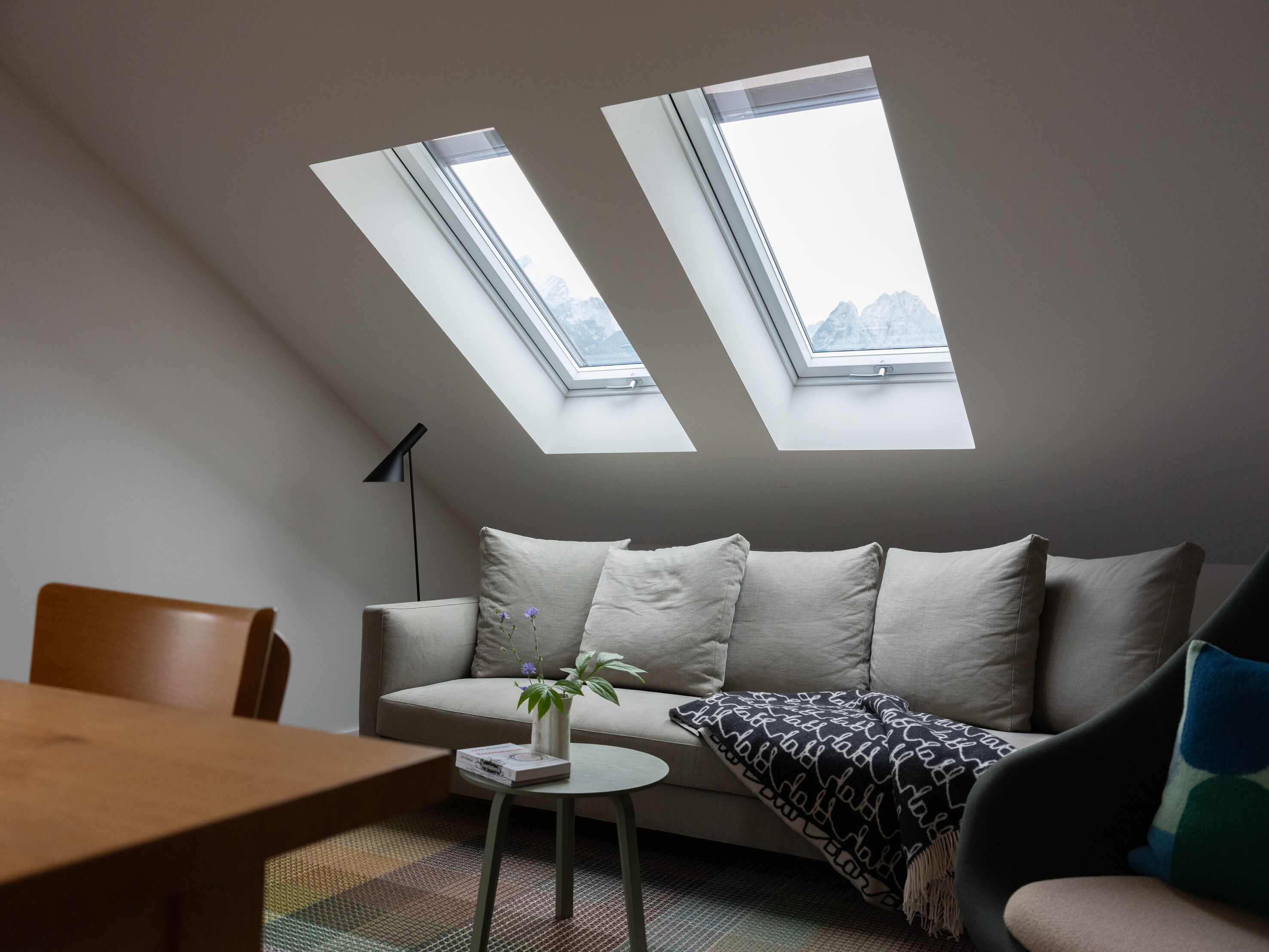 Ein modernes Schlafzimmer im Loft-Stil mit Dachfenstern, einer Couch, einem Couchtisch und einem Essbereich.