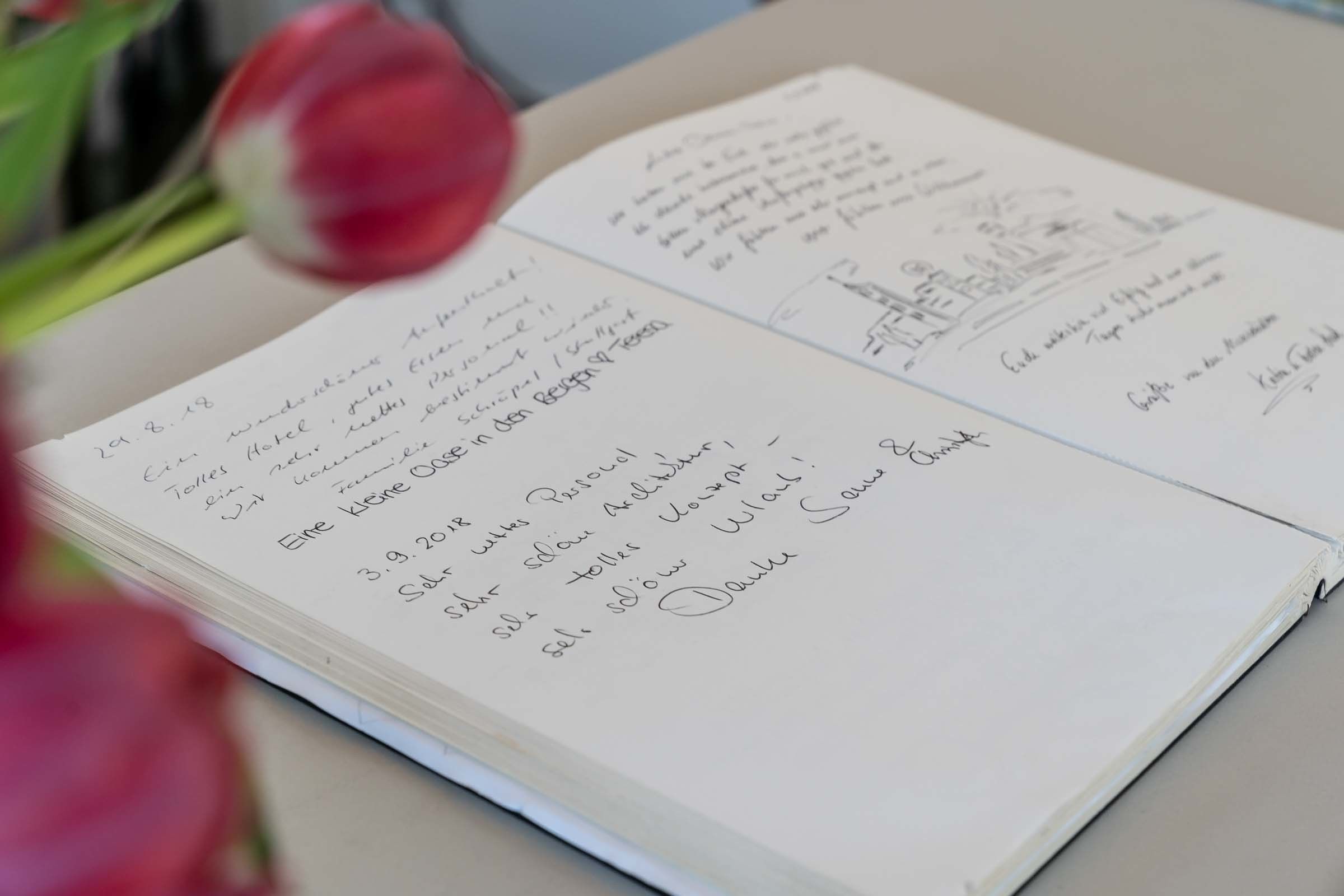 A notebook with handwritten notes and a date, surrounded by red tulips.