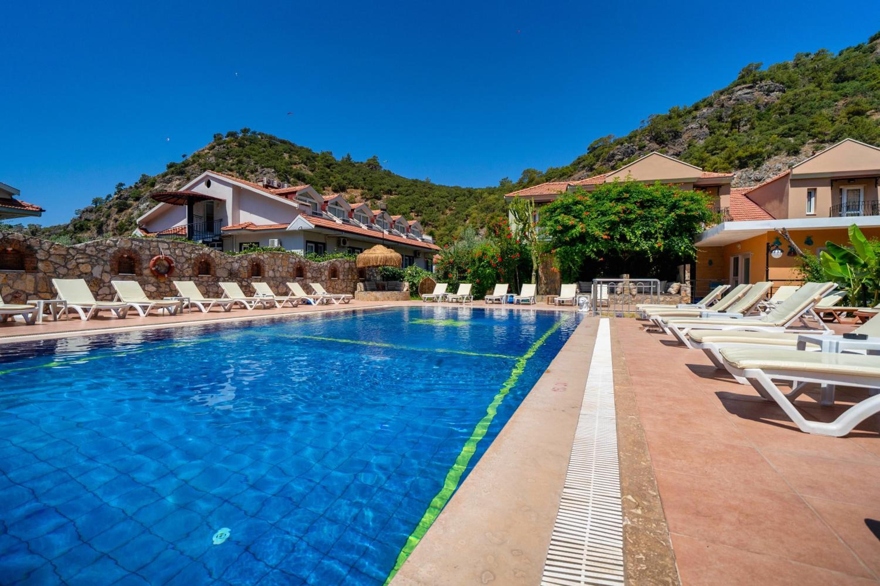 A swimming pool with lounge chairs and a stone wall.