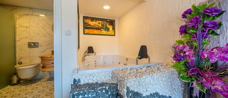 A bathroom with a bathtub, a toilet, and a shower area.