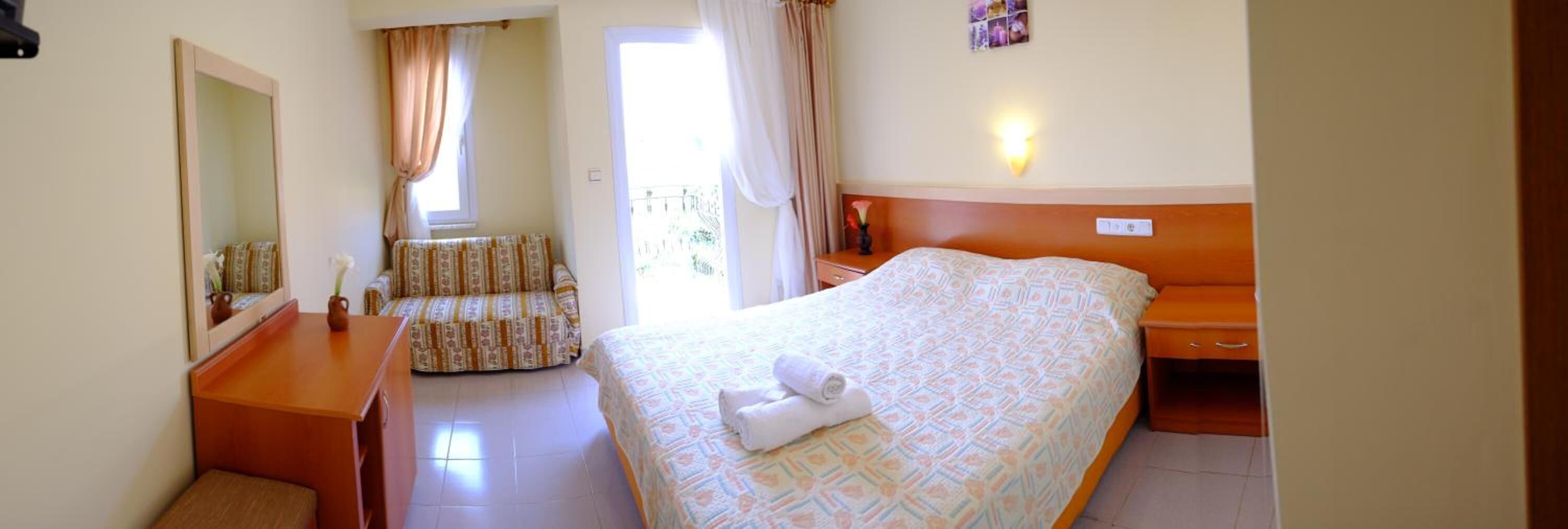 Una habitación de hotel con cama, una silla, un escritorio y un espejo.