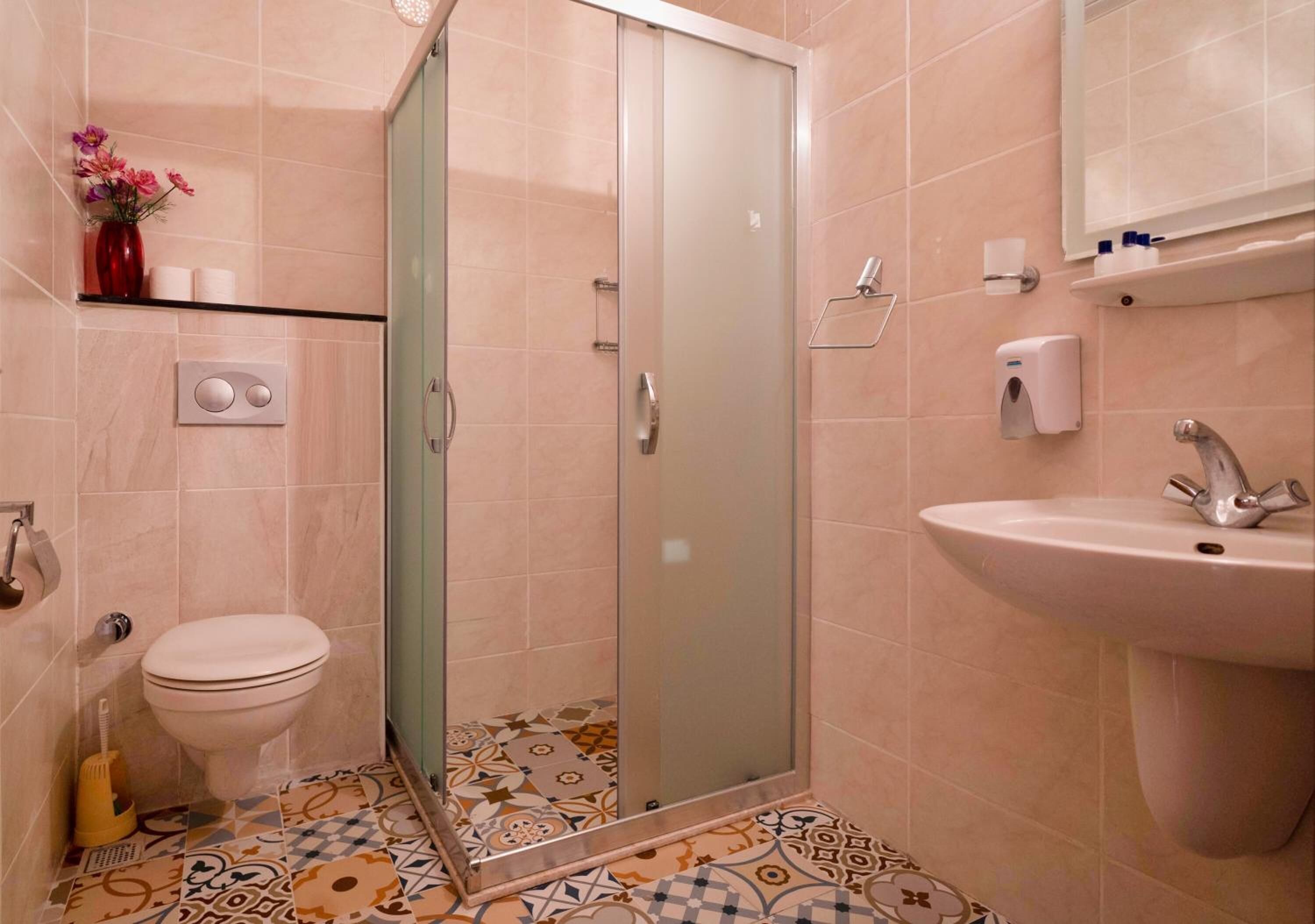 A bathroom with a toilet, shower, sink, and decorative tiles.
