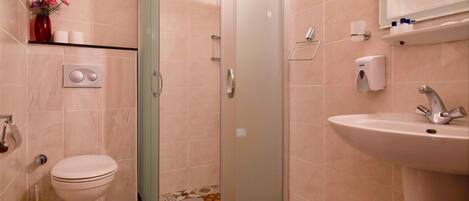 A bathroom with a toilet, shower, sink, and decorative tiles.