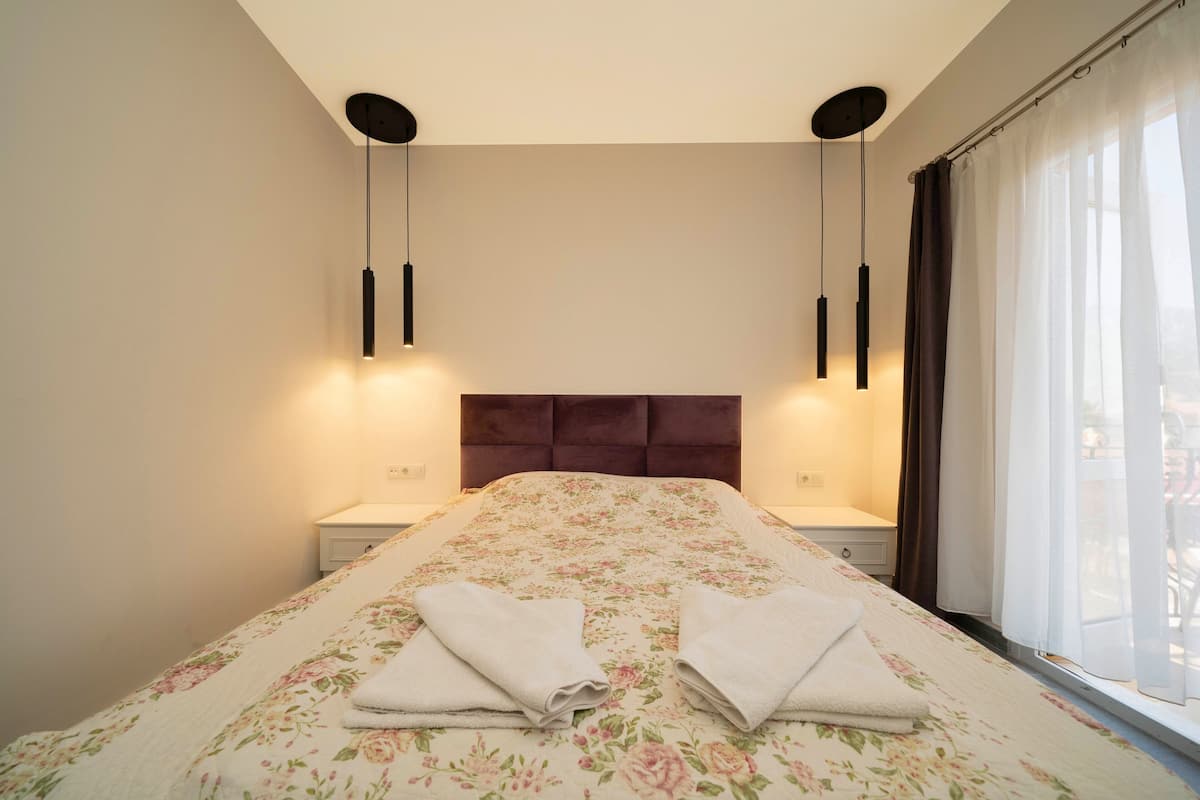 A neatly made bed with floral bedding and two towels folded at the foot.