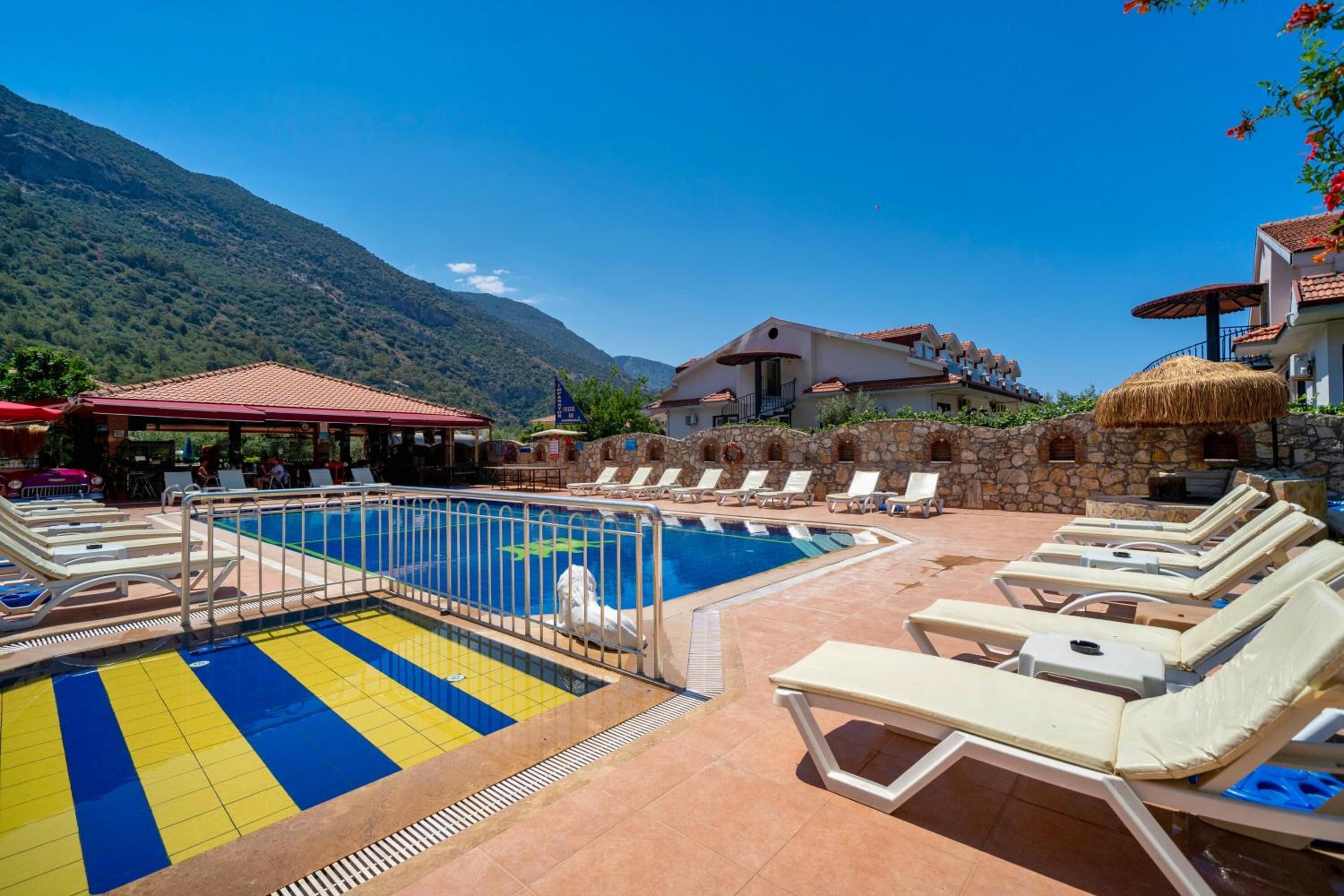 A pool area with lounge chairs and a stone wall.