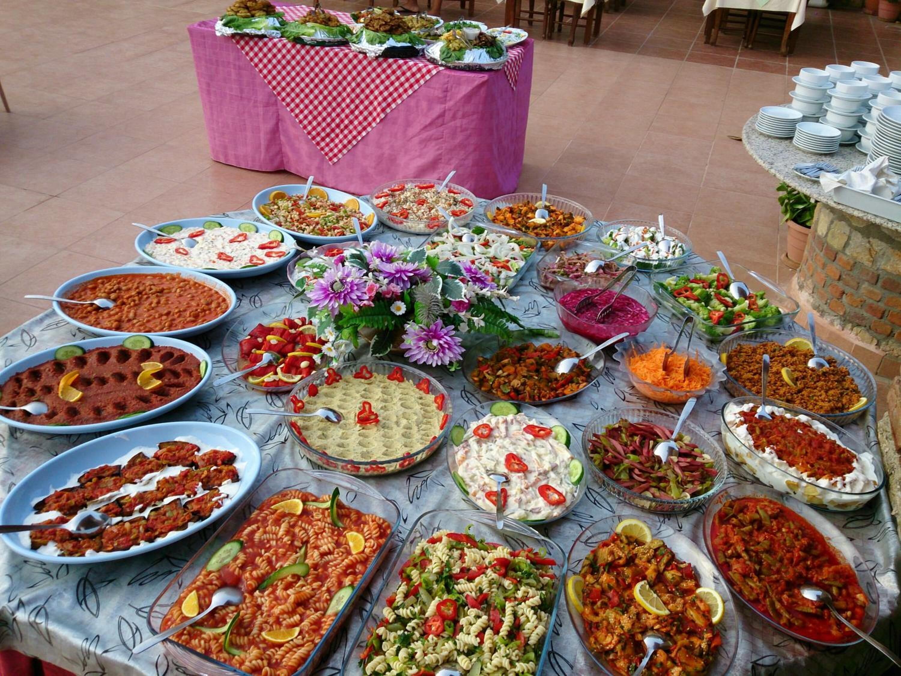 A buffet table with various dishes, including pasta, salads, and dips, arranged on a patterned tablecloth.