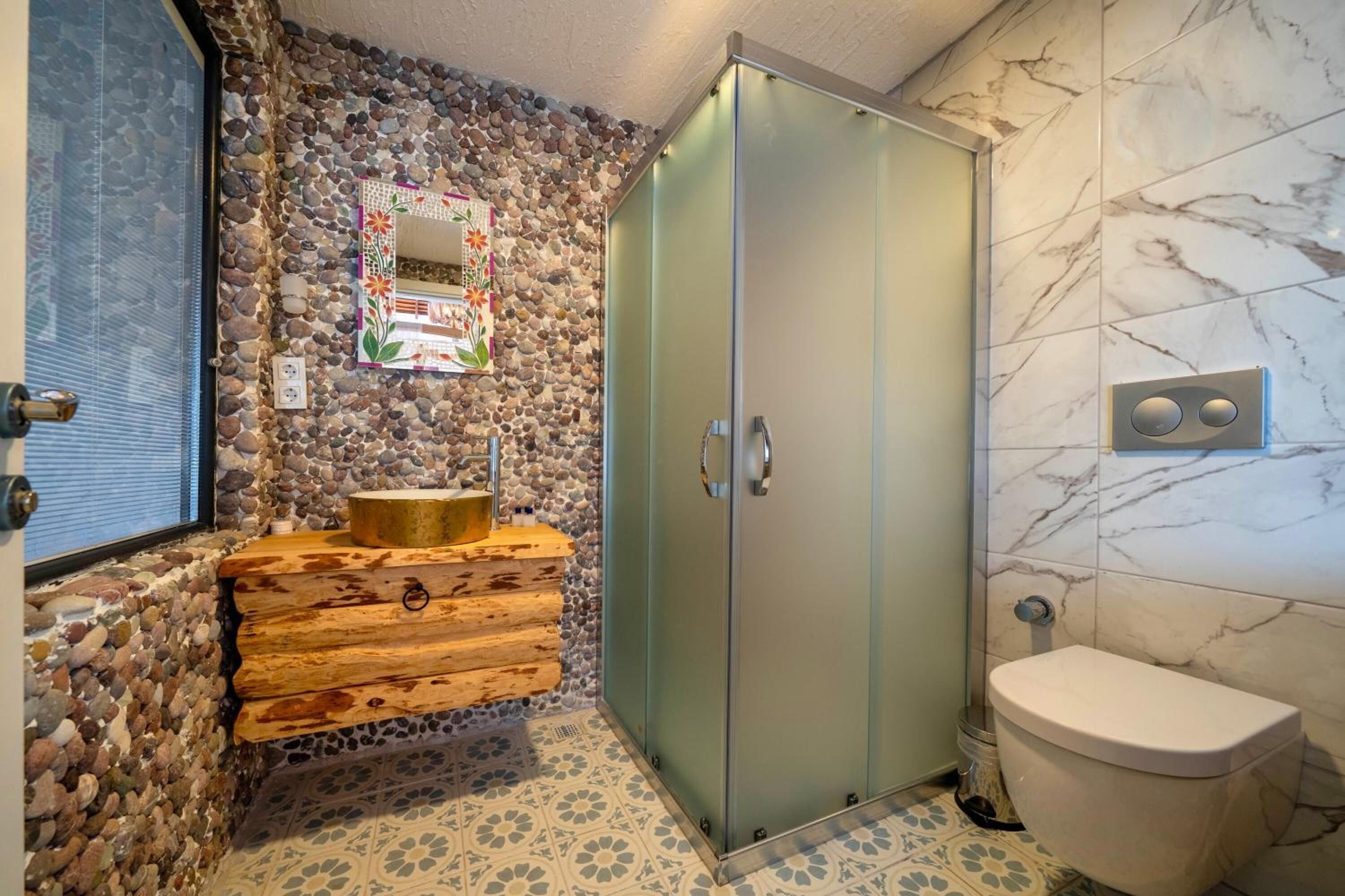 A bathroom with a stone wall, wooden vanity, and a toilet.