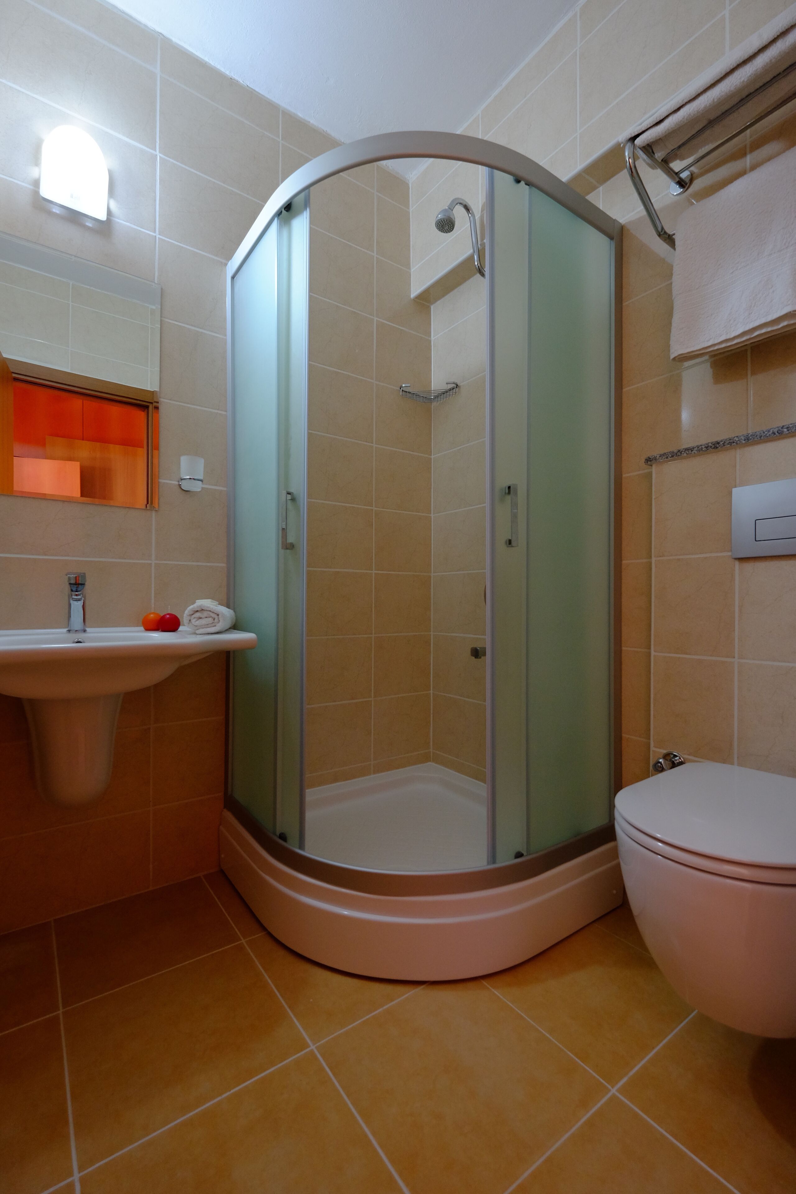 A bathroom with a glass-enclosed shower, a sink, and a toilet.