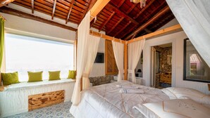 Un dormitorio con una cama grande, cabecera de madera y vista al mar.