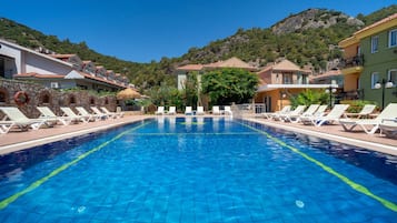 Alberca al aire libre, sombrillas en la alberca y camastros