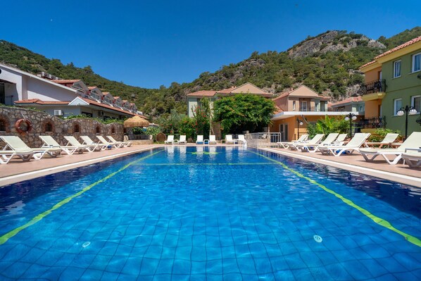 Una piscina al aire libre, sombrillas, sillones reclinables de piscina